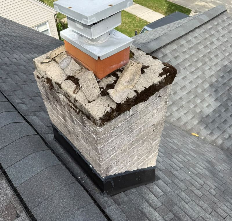 Concrete chimney crown broken into loose chunks with moss in the cracks