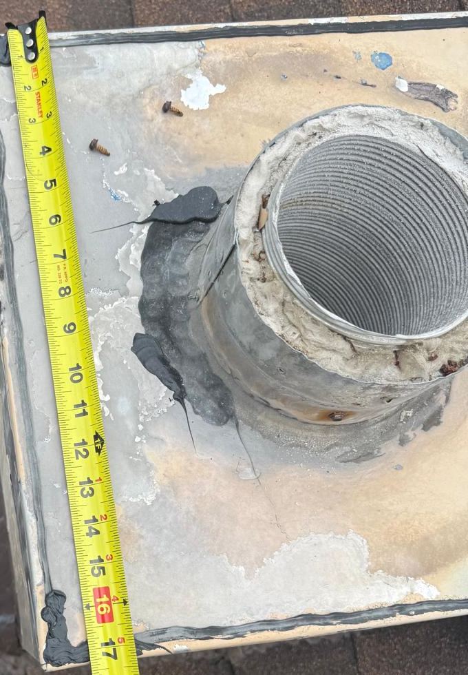 Tape measure laid across the top of a chimney beside a metal flue collar